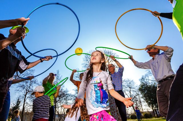 Erwachsenen und Kinder bei Sport und Spiel im Freien.