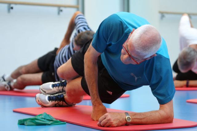 Die Teilnehmer eines Fitnesskurses befinden sich in einer seitlichen Liegestütz.