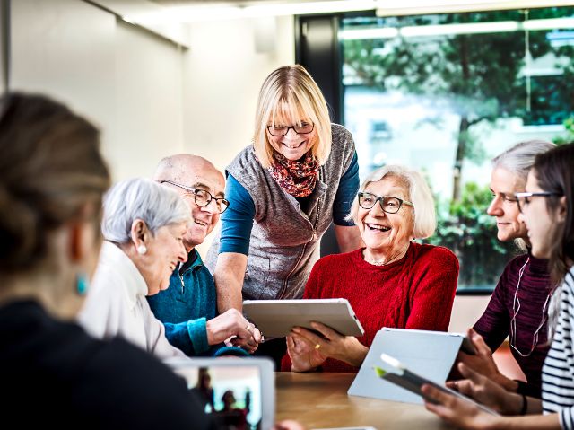 Personen unterschiedlichen Alters besuchen motiviert einen Kurs zur Tabletanwendung.