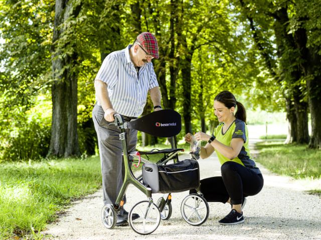 Mitarbeiterin erklärt einem Kunden die Funktionen von seinem neuen Rollator.