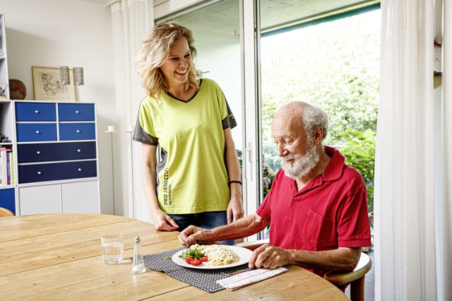 Pro Senectute Mitarbeiterin bereitet eine Mahlzeit für die Klientin zu