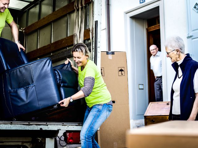 Zwei Mitarbeitende befördern den grossen Sessel eines Ehepaares in einen Umzugswagen.